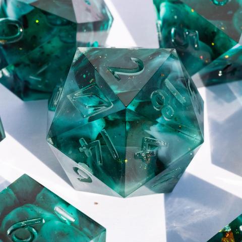 A teal D20 with swirls surrounded by parts of other dice.