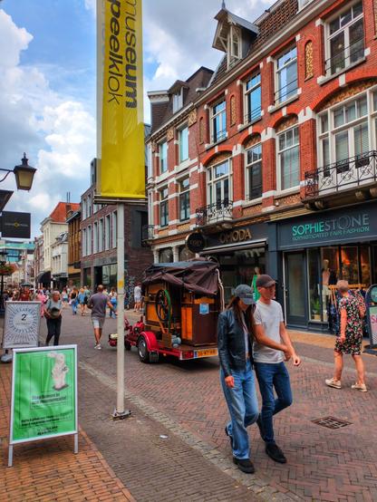 The self-playing organ rolls past three-storey brick buildings with shops on the ground floor.
