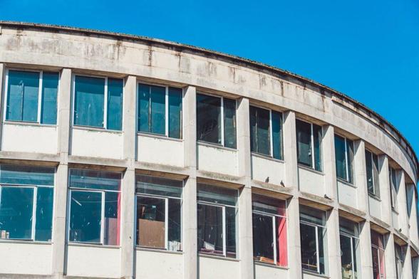 Close-up of a curved, decaying building in liverpool, highlighting its broken windows and state of disrepair, representing construction insolvencies