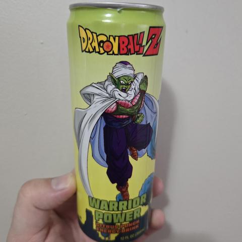 Photograph of a white person's hand holding a green can against a light colored wall. On the can it reads "Dragon Ball Z" at the top and "Warrior Power" at the bottom. In the center is Piccolo standing above a landscape posing to attack.