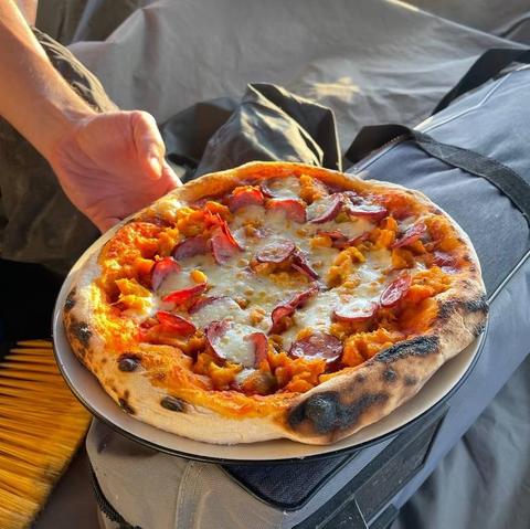 Nel centro della foto una pizza condita con sugo, salsiccia e mozzarella.