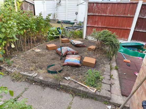 bags of manure and large compost blocks on top of freshly dug bed.