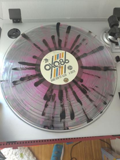 record on the player. clear vinyl with pink shimmer and black stripes