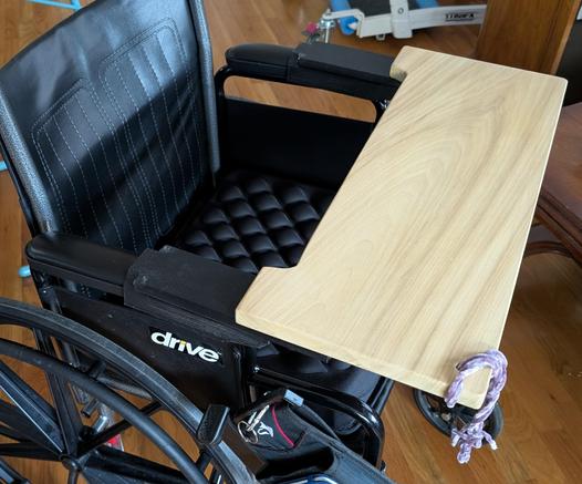 Wood tray on a drive wheelchair with black mounts.