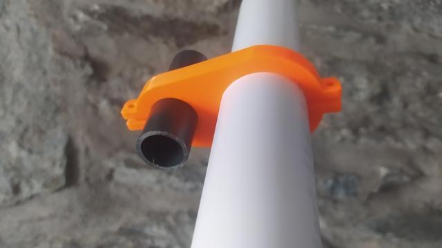 A larger white pipe is clamped to a smaller dark grey pipe with an orange 3d printed clamp section.
