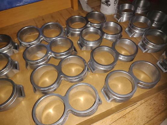A photo of several silver coloured Minions type glasses laying on a piece of cardboard on the floor. The photo is illuminated by a harsh photo flash.