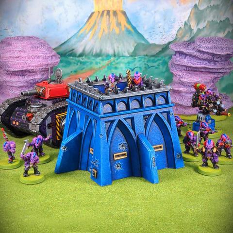 A bright blue model bunker surrounded by brightly coloured model aliens on a bright green model lawn in front of some bright pink model rock formations.