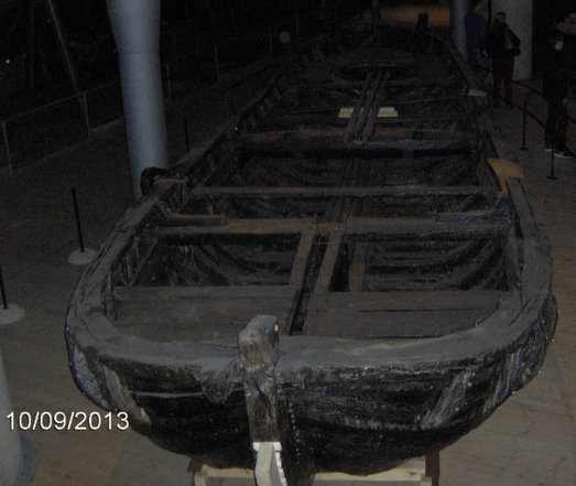Photo of an old lifeboat from the Vasa, after centuries underwater, it's blackened, as its colors had washed away. Bit hard to properly see, the museum further on looking a bit dark.