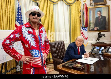 Kid Rock standing in the Oval Office next to Trump sitting at his desk.  Kid Rock is wearing a red outfit with USA flags and white stars