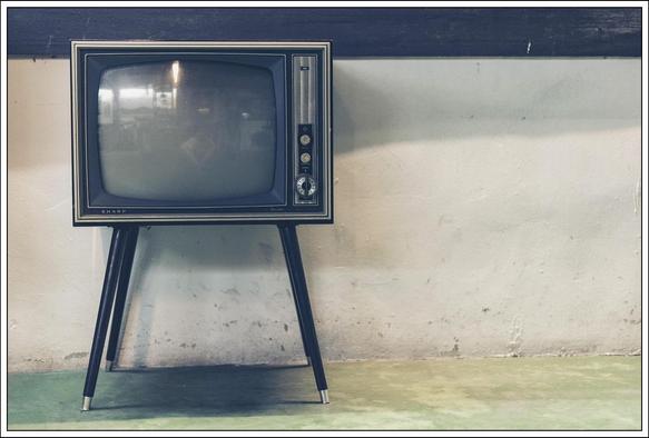Bildbeschreibung: 
Ein alter Schwarz-Weiß-Fernseher vor einer Wand mit abgeblätterter Farbe.
