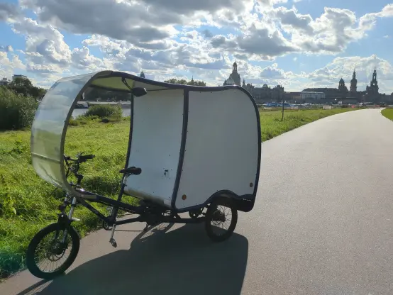 Das CargoTrike, mit weißen Flächen der Kabine, steht auf dem Elbradweg in Dresden.