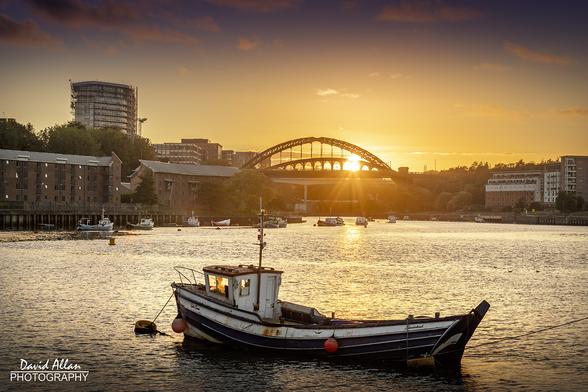 The first sunset of autumn, as captured in Sunderland, North East England. A small fishing boat in the foreground on the River Wear and the sun setting behind some of the city's bridges a little further upstream.