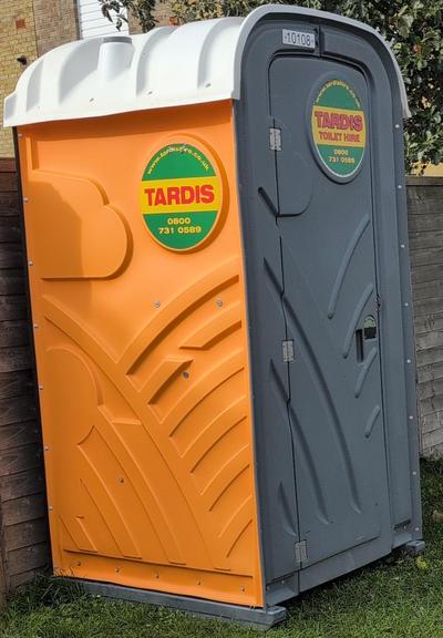 temporary outside toilet, presumably for builders, on a housing estate, with signs saying "TARDIS"