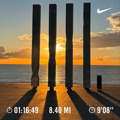 8.4 miles run and orange-gold sunrise in Barcelona over the water behind 4 pillars