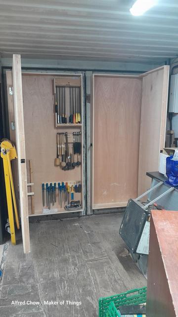 The same view as previously, but with the plywood doors opened revealing them as large shallow cabinets. The left hand cabinet has hanging racks for hammers, mallets, rasps and hand saws. There is still lots of space inside.