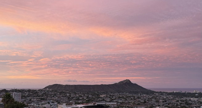 Diamond Head at sunrise. The sky is a beautiful, peaceful mix of pink and light blue.