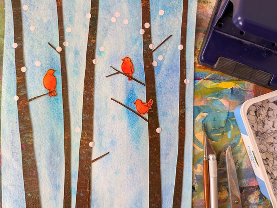 Vögel in einem Winterwald ist eine handgefertigte Papiercollage der Künstlerin Karen Kaspar.
In einer verschneiten Winterlandschaft in sanften Blautönen sitzen drei leuchtend rote Vögel auf kahlen Ästen von hohen, schlanken Baumstämmen, die sich dunkelbraun gegen den hellen winterlichen Hintergrund abheben. Große weiße Schneeflocken fallen.
Die Baumstämme und Äste wurden mit Acrylfarbe auf Papier gemalt und dann als Collage auf den mit Aquarellfarben gemalten Hintergrund montiert und mit den aquarellierten Vögeln kombiniert.
Das Winterbild ist minimalistisch gehalten und vermittelt eine ruhige und friedliche Stimmung.
Neben dem Bild sind Pinsel, Cutter, Schere, Locher.