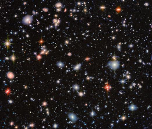 From source linked in toot: An area of deep space with thousands of galaxies in various shapes and sizes on a black background. Most are circles or ovals, with a few spirals. More distant galaxies are smaller, down to being mere dots, while closer galaxies are larger and some appear to be glowing. Red and orange galaxies contain more dust or more stellar activity