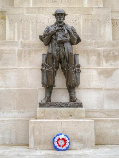 Statue of a ww1 soldier with artillery shells in large pouches on his legs.