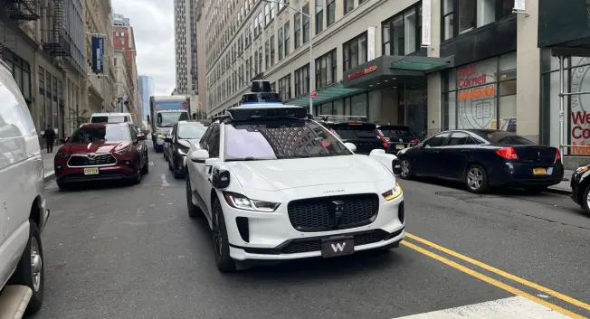 A waymo car rolling on a Manhattan street.