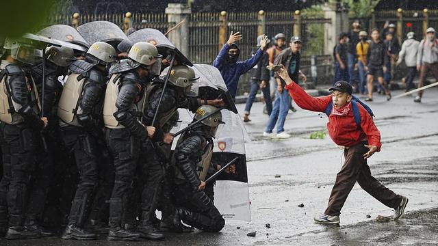 A demonstrator throws a rock at police during a protest against lavish allowances given to parliament members in Jakarta, Indonesia, Aug. 28, 2025. (AP Photo/Achmad Ibrahim)